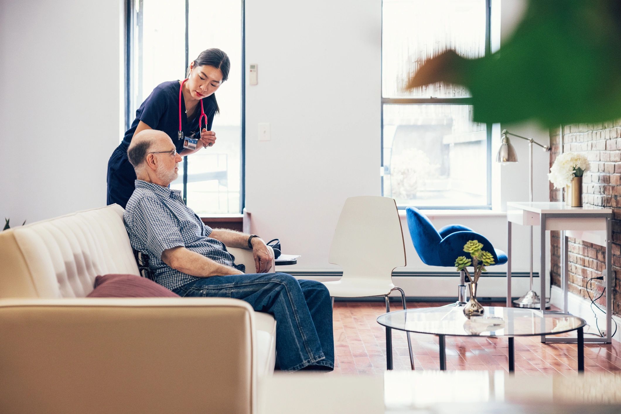 Home health nurse supervising senior man in living room
